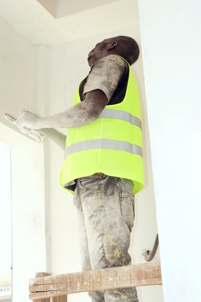 Peintre en gilet de sécurité appliquant une finition murale